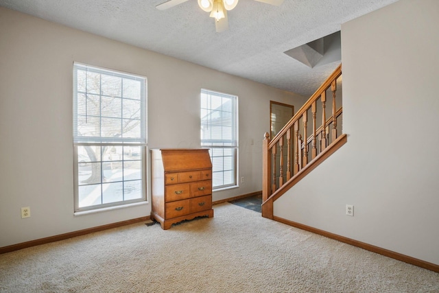 carpeted empty room with baseboards, a textured ceiling, and a healthy amount of sunlight