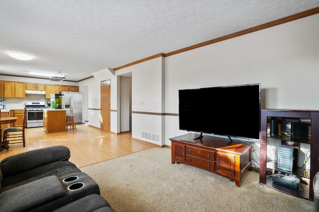 living area with light colored carpet, visible vents, ornamental molding, a textured ceiling, and baseboards