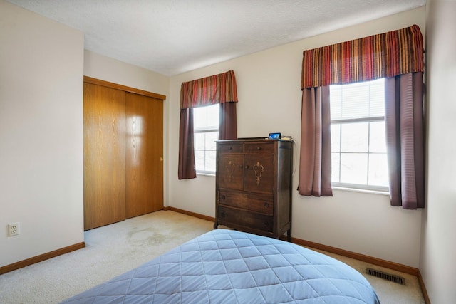 carpeted bedroom featuring baseboards, multiple windows, and visible vents