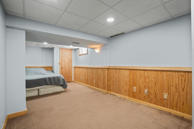 unfurnished bedroom with carpet floors, wood walls, a paneled ceiling, and a wainscoted wall