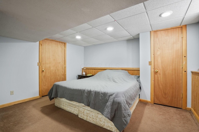 carpeted bedroom with baseboards, a drop ceiling, and recessed lighting