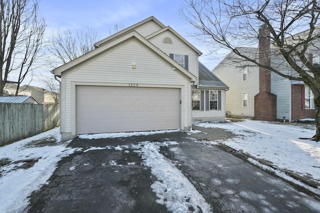 traditional-style house featuring fence, driveway, and an attached garage