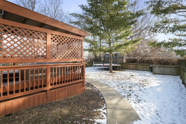 yard layered in snow featuring a trampoline and a fenced backyard