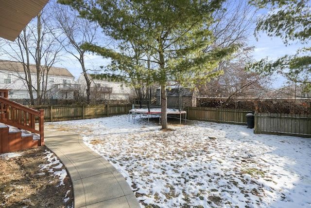 yard covered in snow with a fenced backyard and a trampoline