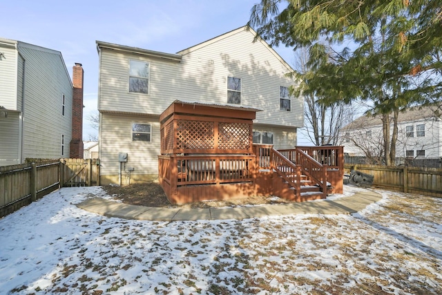 snow covered house featuring a fenced backyard and a wooden deck