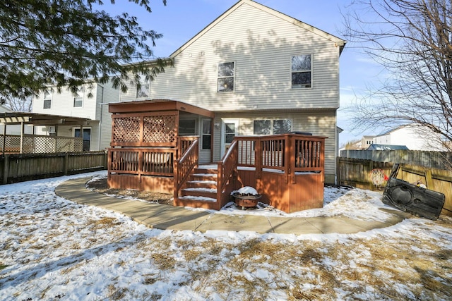 snow covered house with a fenced backyard and a wooden deck