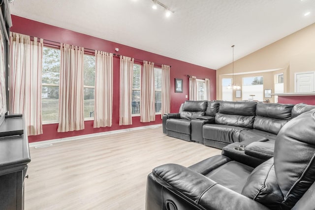 living area featuring lofted ceiling, a notable chandelier, visible vents, light wood-style floors, and rail lighting