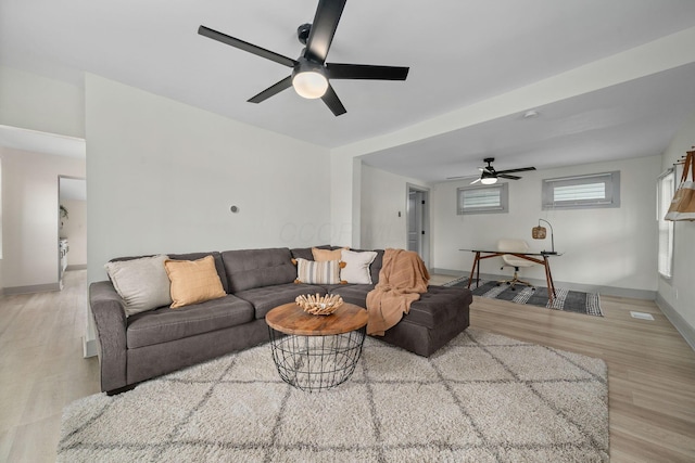 living area featuring ceiling fan, baseboards, and wood finished floors