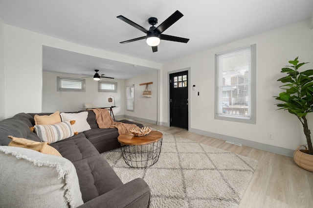 living area with ceiling fan, baseboards, and wood finished floors