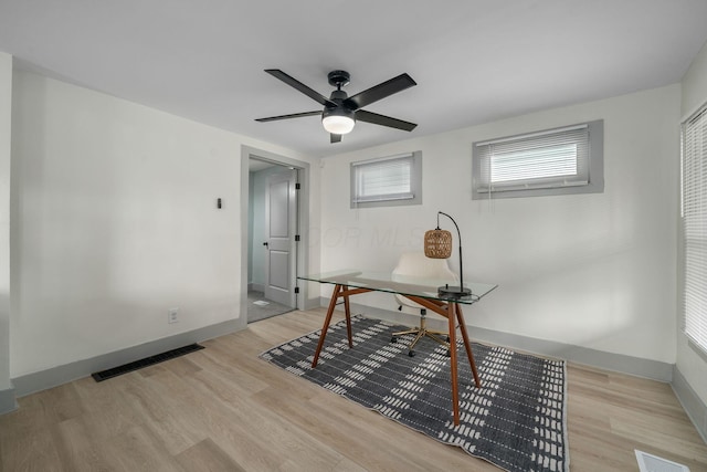 office space with light wood-type flooring, visible vents, and baseboards