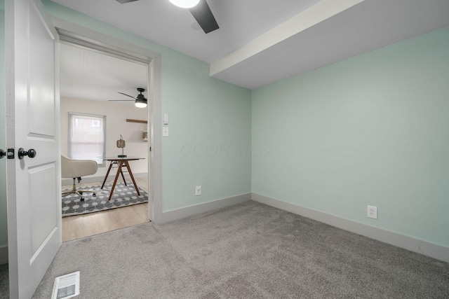 carpeted empty room featuring baseboards, visible vents, and ceiling fan