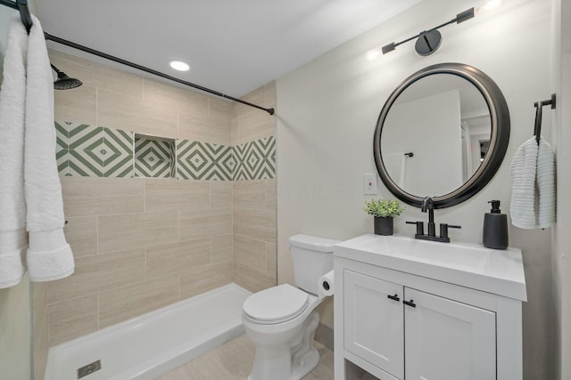 bathroom with tiled shower, vanity, and toilet