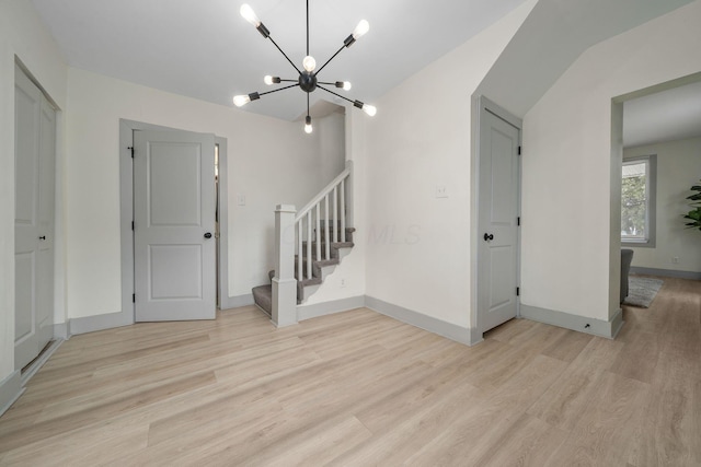 unfurnished room with light wood-type flooring, stairway, baseboards, and an inviting chandelier