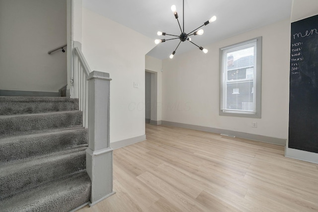 stairway with a notable chandelier, baseboards, and wood finished floors