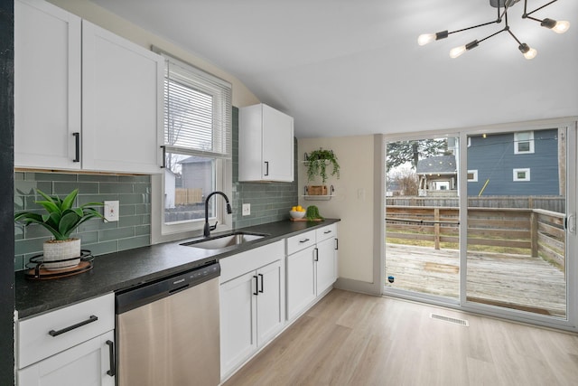 kitchen with plenty of natural light, visible vents, dishwasher, dark countertops, and a sink