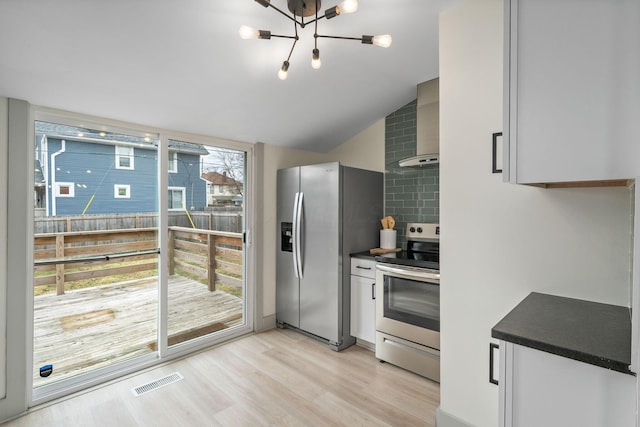 kitchen featuring appliances with stainless steel finishes, dark countertops, visible vents, and wall chimney exhaust hood