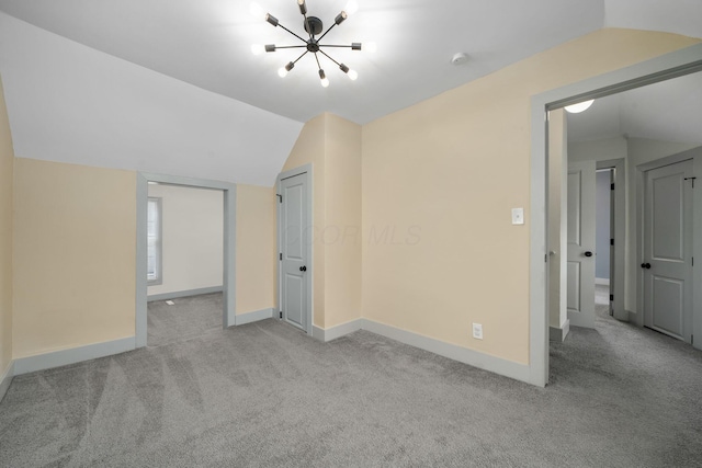 interior space with carpet floors, baseboards, vaulted ceiling, and a chandelier