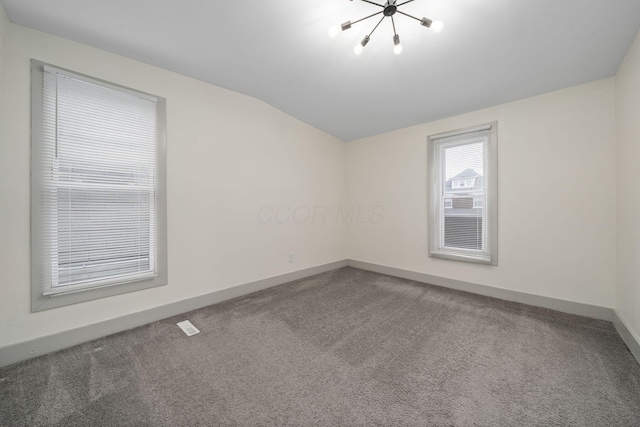 carpeted empty room featuring vaulted ceiling and baseboards