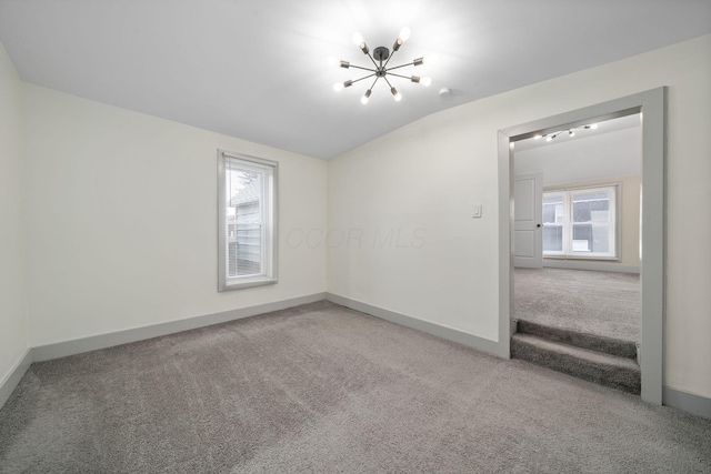 carpeted spare room featuring vaulted ceiling, a chandelier, and baseboards