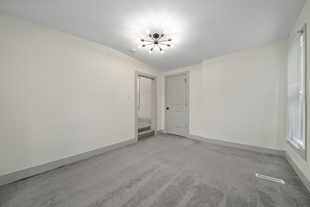 unfurnished room featuring a chandelier, light colored carpet, and baseboards