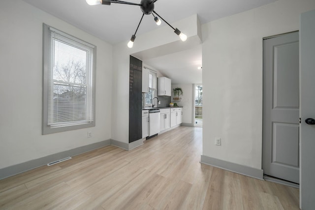 kitchen with visible vents, white cabinets, stainless steel dishwasher, light wood-type flooring, and decorative backsplash