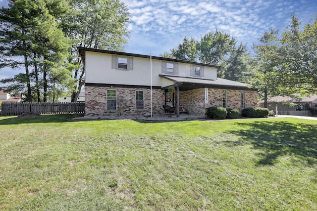 view of front of house with brick siding, fence, a front lawn, and stucco siding