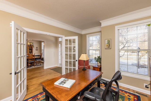 home office featuring french doors, crown molding, visible vents, wood finished floors, and baseboards