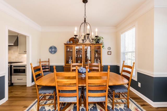 dining space featuring an inviting chandelier, crown molding, baseboards, and wood finished floors