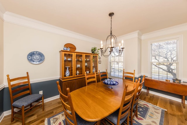 dining area with crown molding, baseboards, a notable chandelier, and wood finished floors