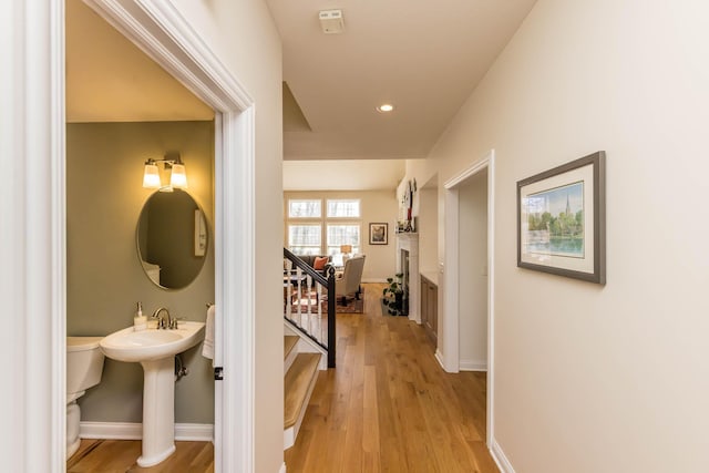 hallway with stairs, light wood finished floors, recessed lighting, and baseboards