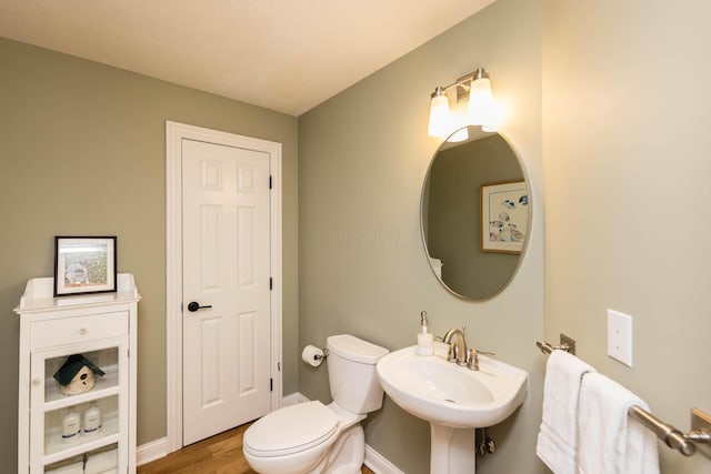 bathroom with toilet, baseboards, a sink, and wood finished floors