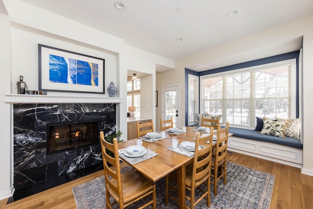 dining area with recessed lighting, wood finished floors, baseboards, and a premium fireplace