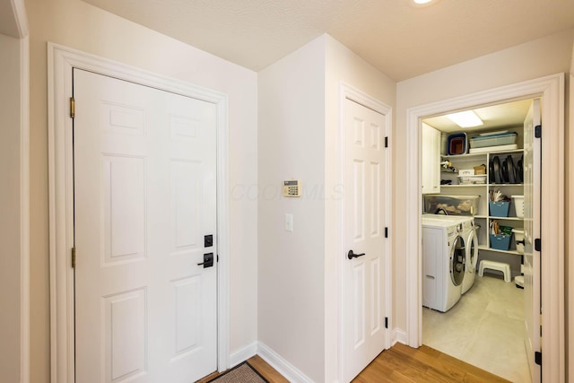 laundry room with laundry area, baseboards, light wood finished floors, and washing machine and clothes dryer