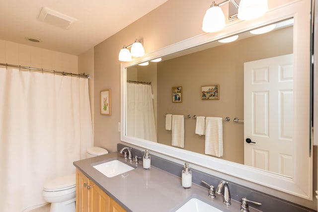 full bath with toilet, double vanity, a sink, and visible vents