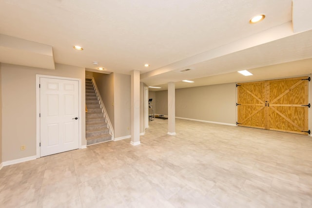 finished below grade area with stairs, a barn door, recessed lighting, and baseboards