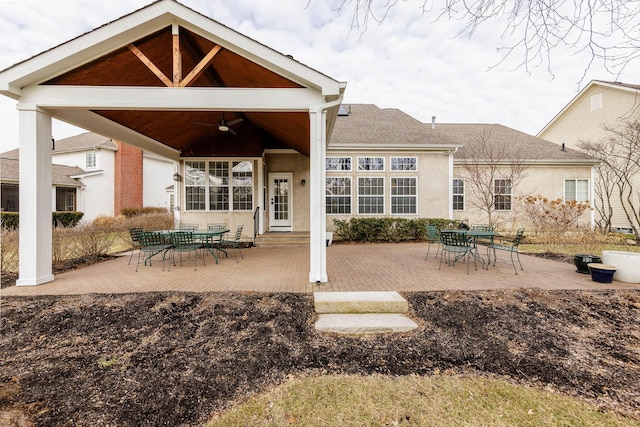 rear view of property featuring roof with shingles, a patio area, a ceiling fan, and stucco siding