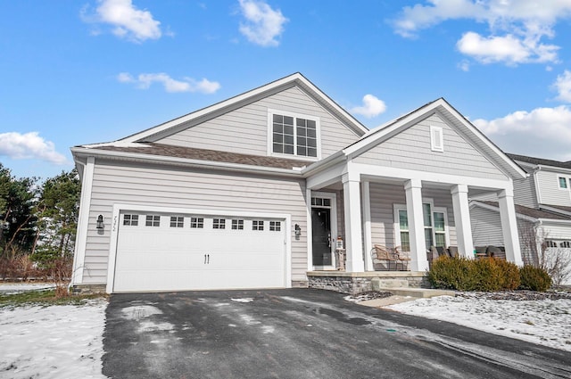 view of front of property with aphalt driveway, covered porch, a shingled roof, and a garage