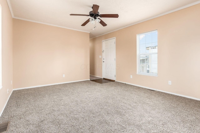 carpeted spare room featuring baseboards, visible vents, ornamental molding, and ceiling fan