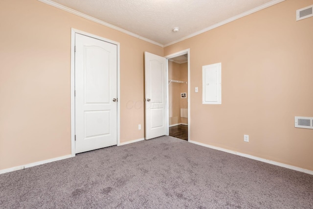 unfurnished bedroom featuring electric panel, visible vents, crown molding, and carpet flooring