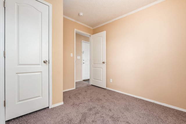 unfurnished bedroom with carpet floors, a textured ceiling, baseboards, and crown molding