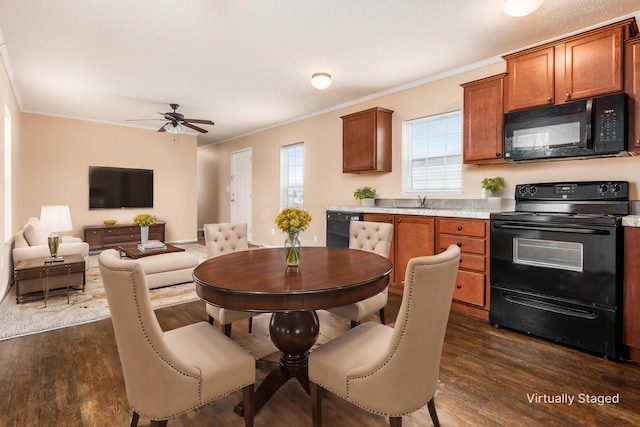 kitchen with black appliances, ornamental molding, dark wood finished floors, and light countertops