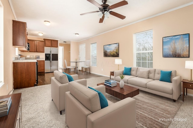 living area featuring baseboards, ornamental molding, and ceiling fan