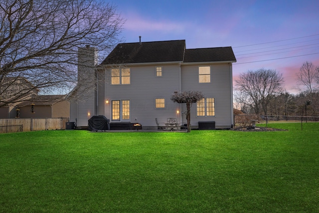 rear view of property featuring a chimney, a lawn, central AC unit, a patio area, and fence