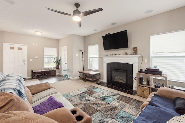 living area with a wealth of natural light, baseboards, ceiling fan, and a tiled fireplace