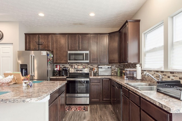 kitchen featuring dark brown cabinets, appliances with stainless steel finishes, backsplash, and a sink