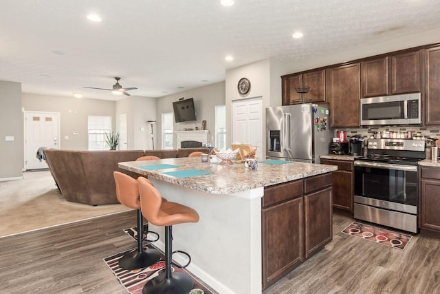 kitchen featuring appliances with stainless steel finishes, wood finished floors, dark brown cabinetry, and a center island