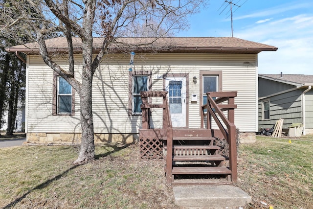 bungalow with roof with shingles and a front lawn