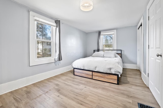 bedroom with baseboards, visible vents, and wood finished floors