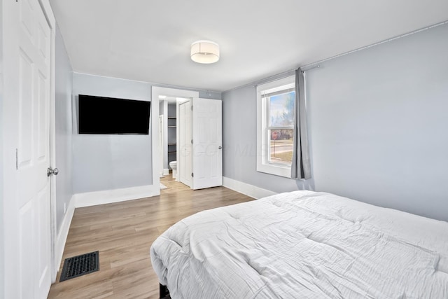 bedroom featuring baseboards, visible vents, and wood finished floors