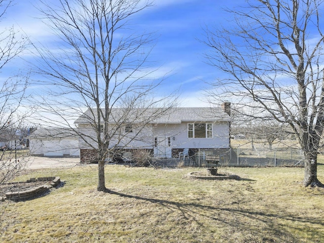 rear view of house featuring a chimney, fence, and a yard